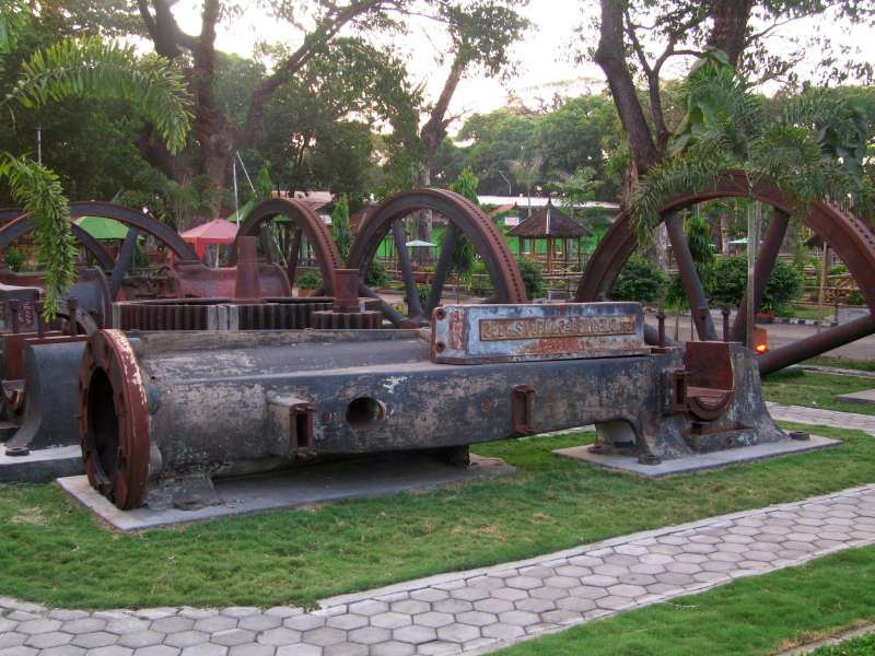 Tasikmadu: Teile der ehemaligen Mühlenmaschinen als Exponate im Freien